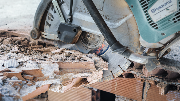 Cutting saw slicing through a rough brick wall.