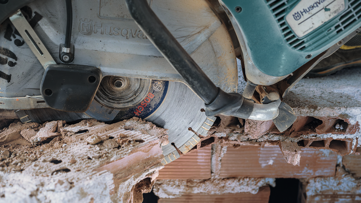 Diamond saw blade cutting through brick and concrete rubble.