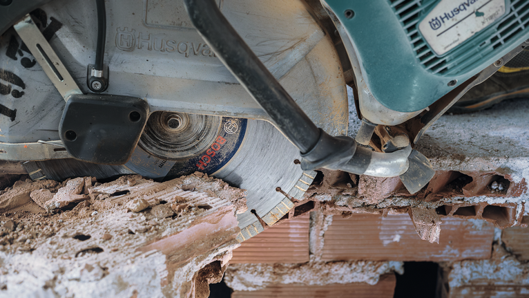 Diamond saw blade cutting through brick and concrete rubble.