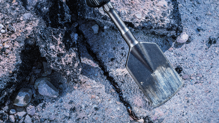 Chisel tool breaking concrete rubble on a construction site.