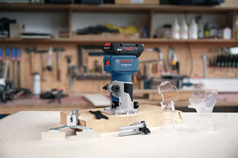 Cordless trim router and attachments displayed on a workbench in a woodworking shop.