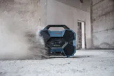 Jobsite radio playing music while dust swirls around it on a construction floor.