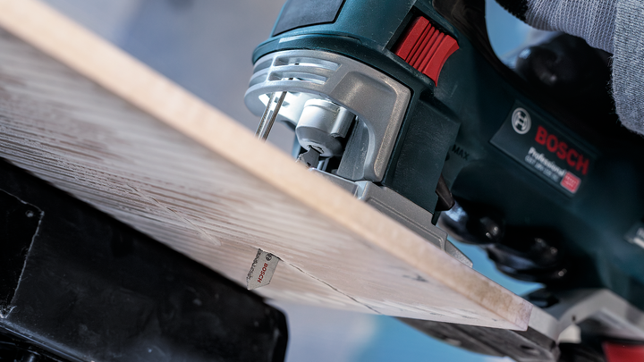 Person guides a jigsaw to cut through a wooden board.