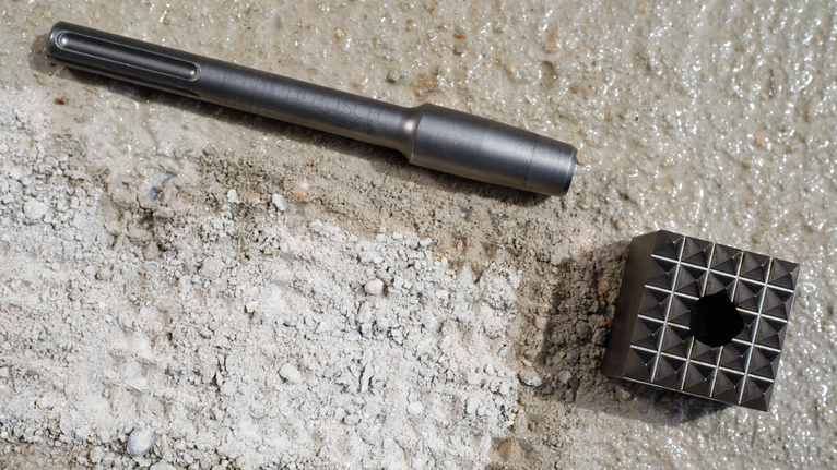 Chisel and a pointed metal tool resting on rough concrete.