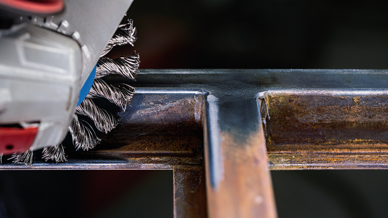 Wire brush tool cleaning welded metal joints.