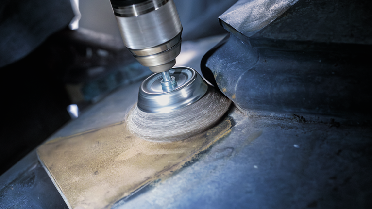 Wire brush attachment polishing a metal surface.
