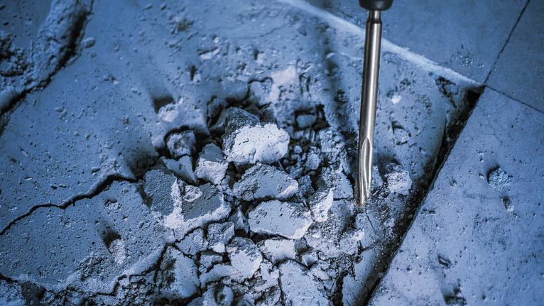 Chisel demolishing cracked concrete floor.