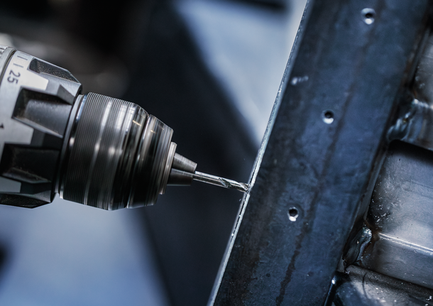 Power drill creating a hole in a metal frame.