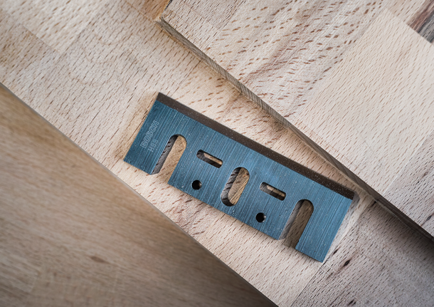 Metal utility blade placed on stacked wooden boards.