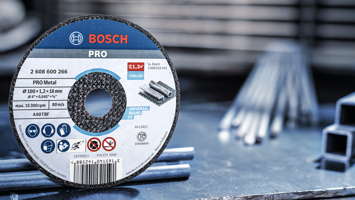 Metal cutting disc on a workbench beside steel rods in a workshop.