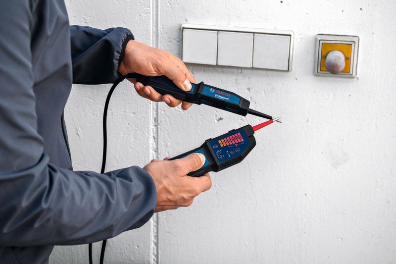Person using a voltage tester near a wall switch.