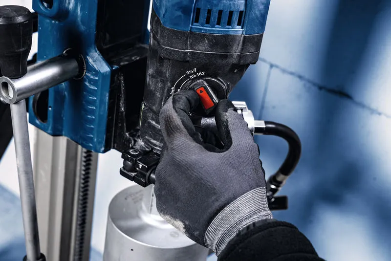 Person wearing safety equipment adjusts a dial on a mounted diamond drill.