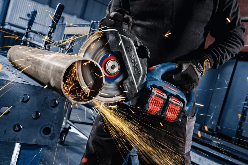 A person wearing safety equipment cuts a metal pipe with a cordless angle grinder.