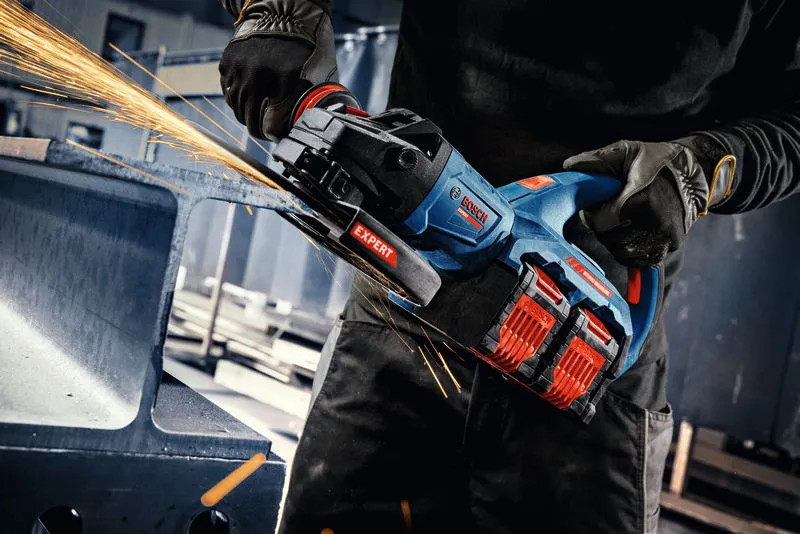 A person wearing safety equipment grinds metal with a cordless angle grinder, producing sparks.