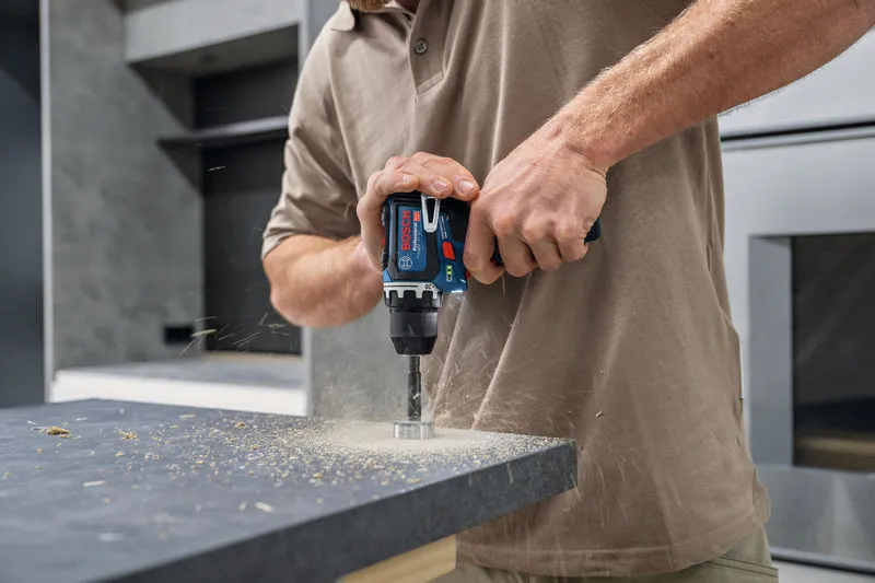 A person drills a hole into a countertop with a cordless power tool.