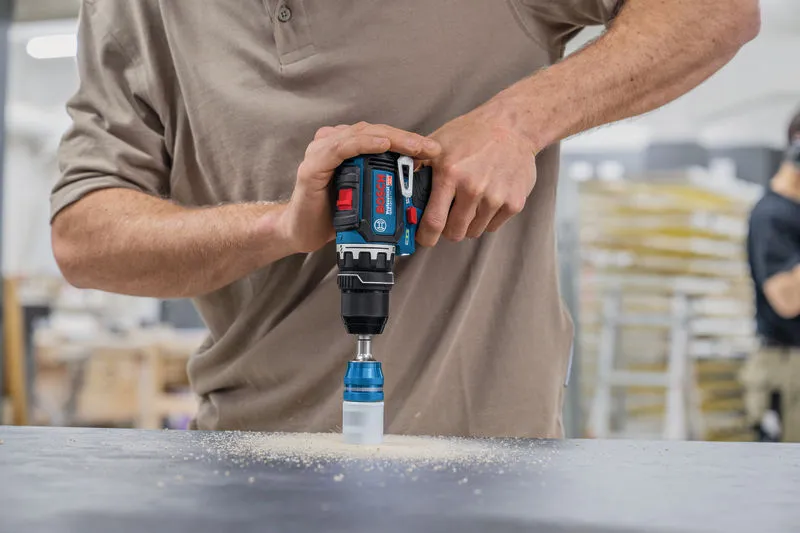 Person operating a cordless drill with a hole saw bit to cut into a work surface.