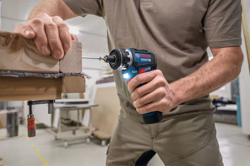 A person drives a screw into stacked wood using a cordless screwdriver.