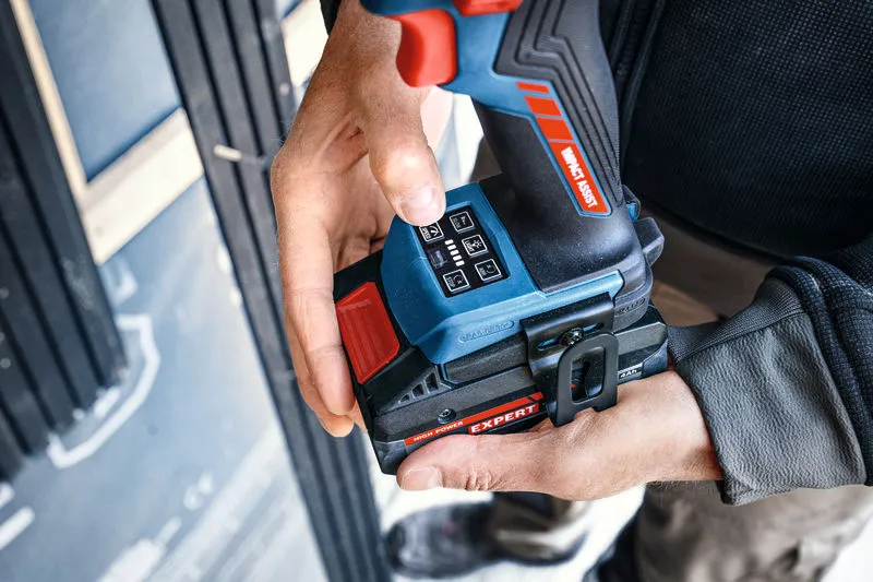 A person adjusts a cordless impact driver wearing safety equipment.