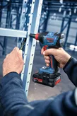 Person uses an impact wrench to fasten a bolt on a metal support frame.