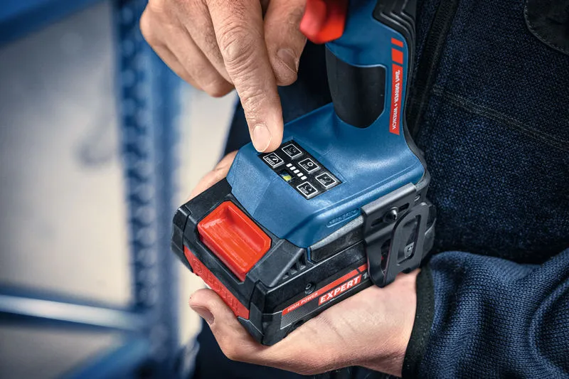 Person adjusts settings on a cordless impact wrench, wearing safety equipment.