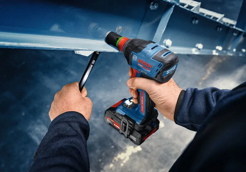 A person uses an impact wrench to fasten a bolt on a steel beam.