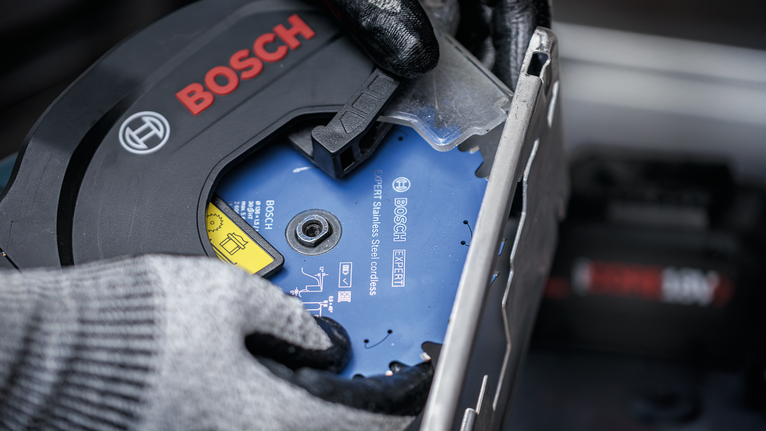 Person wearing safety equipment installs a circular saw blade.