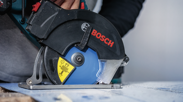Person wearing safety equipment cuts wood with a circular saw.