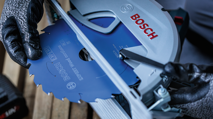 Person wearing safety equipment installs a circular saw blade into a power tool.