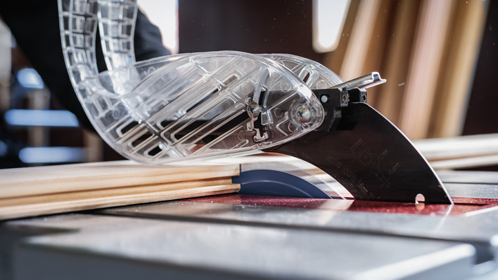 Circular saw with safety guard cutting wooden board in a workshop.