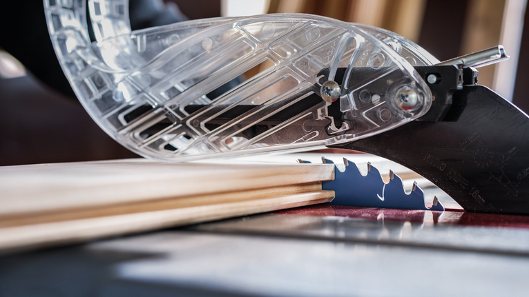 Table saw with protective guard cutting wooden boards.