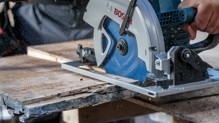 Person operating a circular saw to cut wood on a construction site.
