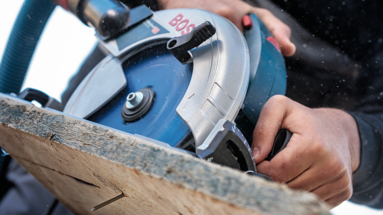 Person operating a circular saw to cut a wooden board.