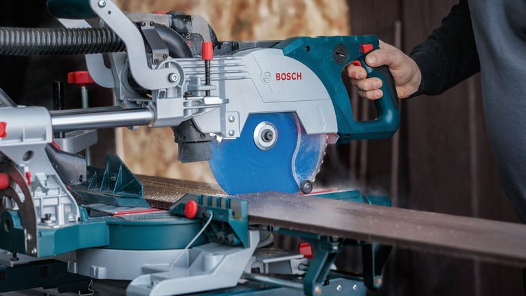 Person guiding a circular saw to cut a wooden board on a miter saw stand.
