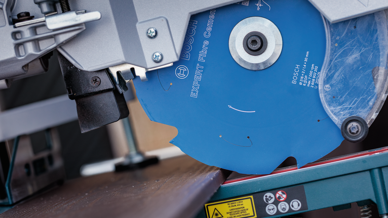 Circular saw blade cutting a brown board in a workshop.