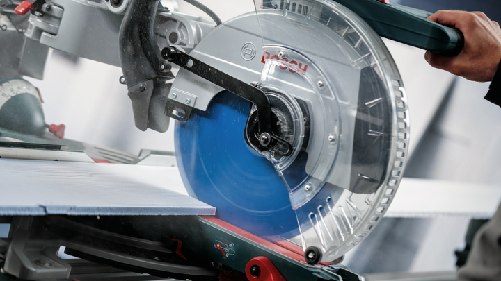 Person operates a circular saw making a precise cut through a large tile.