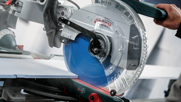 Person operates a circular saw making a precise cut through a large tile.