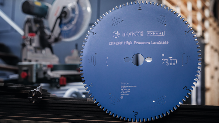 Large circular saw blade displayed in front of a saw machine in a workshop.