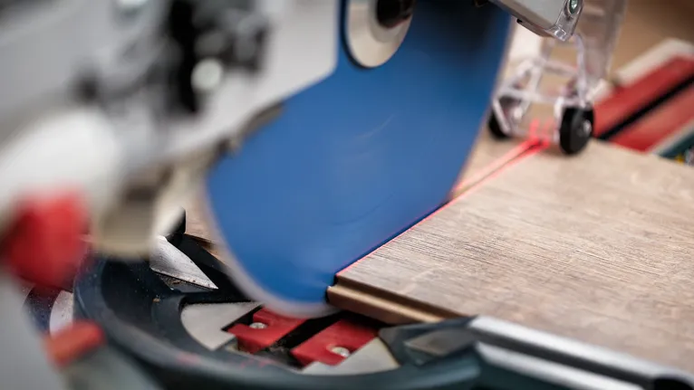 Circular saw cutting a wood board along a red laser guide line.