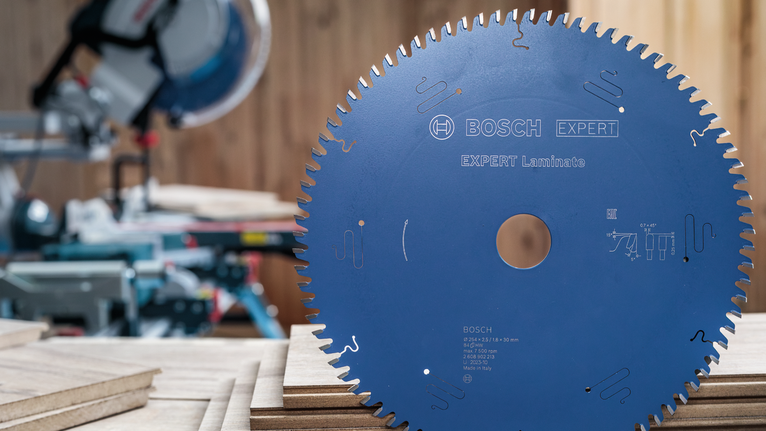Large circular saw blade standing upright on stacked wooden boards in a workshop.