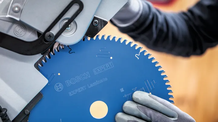 Person wearing safety equipment installs a circular saw blade into a cutting machine.