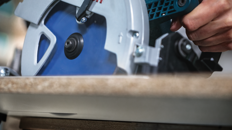 Person uses a circular saw to cut wood.