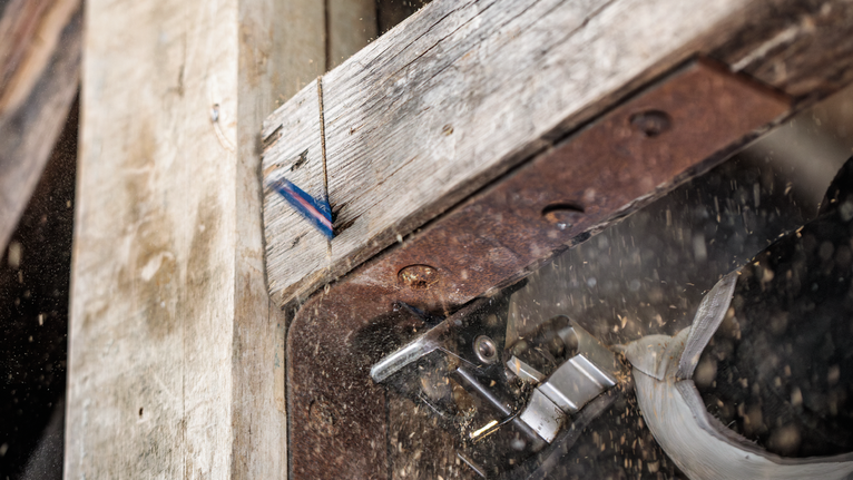 Jigsaw cutting through a wooden plank, creating dust and debris.