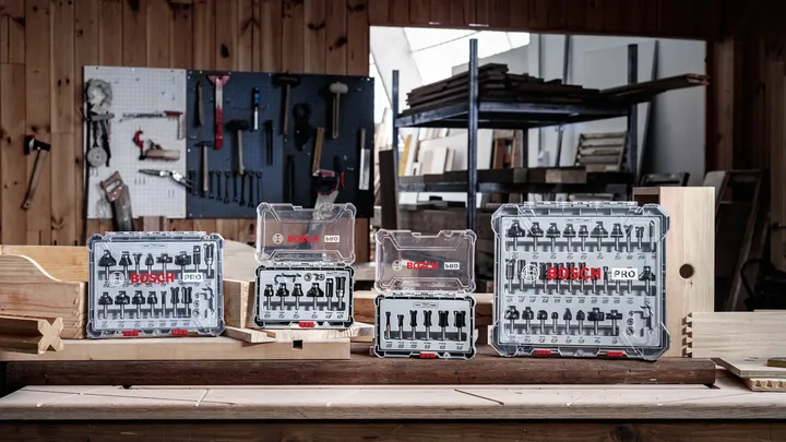 Router bit and screwdriver bit sets displayed on a woodworking bench in a workshop.