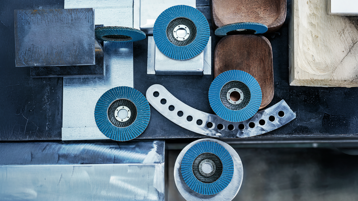 A set of blue abrasive wheels arranged on a metal workbench with various materials.