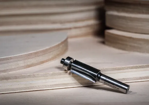 Router bit placed on layered plywood, ready for woodworking applications.