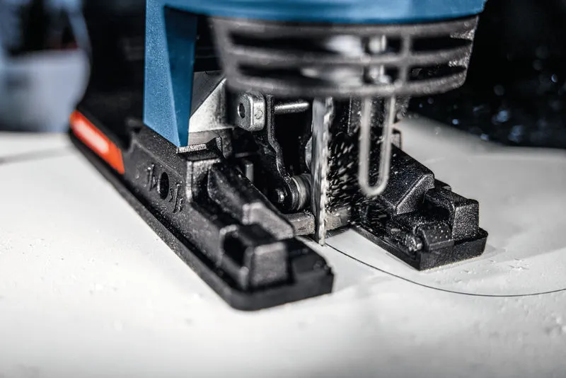 A jigsaw cutting a curved line in a white board.