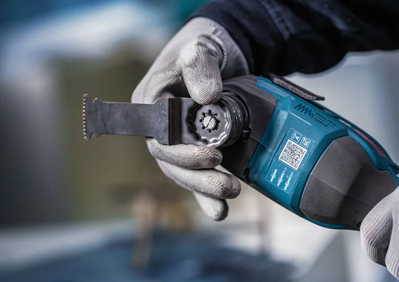 A person wearing safety equipment attaches a blade to a cordless multi-cutter.