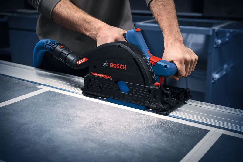 A person guides a cordless plunge saw along a track to cut a panel.