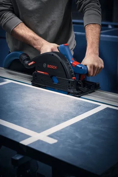 A person guides a cordless plunge saw along a track to cut a panel.