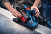 Person adjusts a cordless plunge saw on a guide rail.